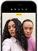 iPhone 18 Pro, สีดำ, ภายนอกด้านหน้า, แสดงให้เห็นสองคนกำลังโพสท่าให้กล้องเพื่อสาธิตกล้องหน้า Center Stage